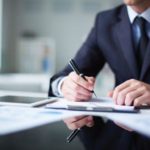 Close-up of male hands with pen over document